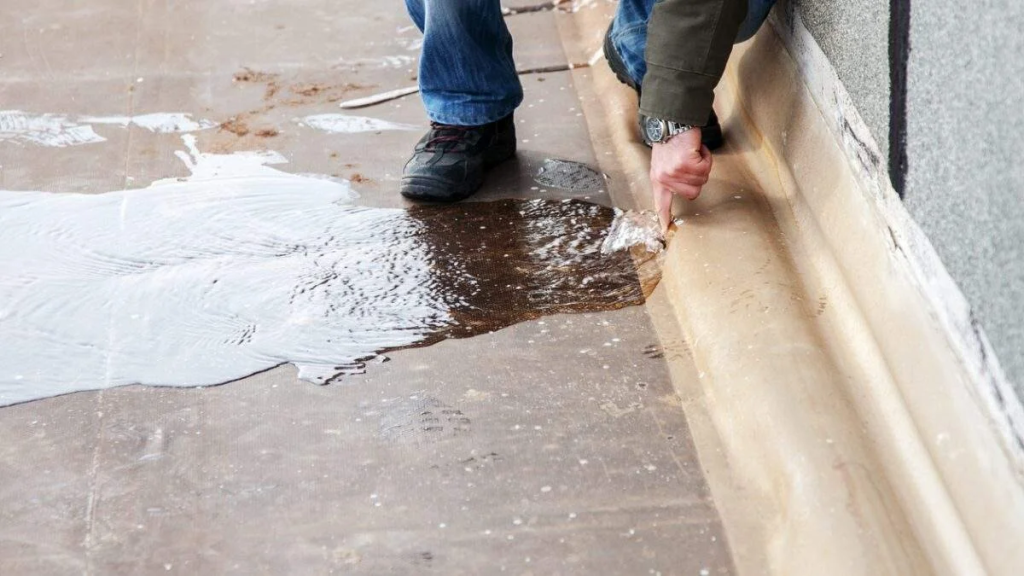 Man pressing the base of a building from which water is leaking out.