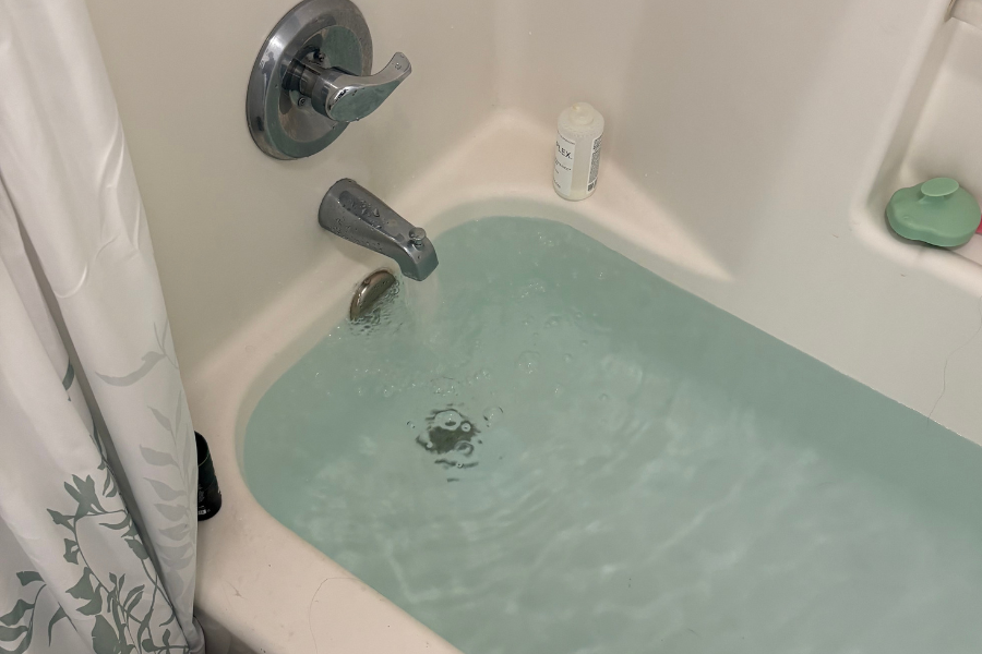A fiberglass bathtub filled with water coming out from the spout.