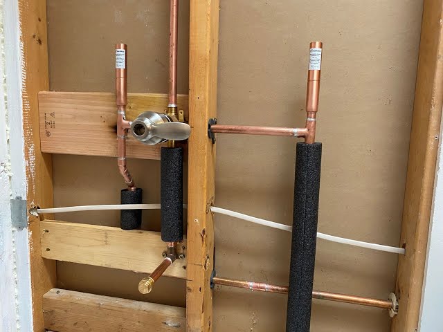 New copper pipe shower valve and water line installation inside an open wall frame.