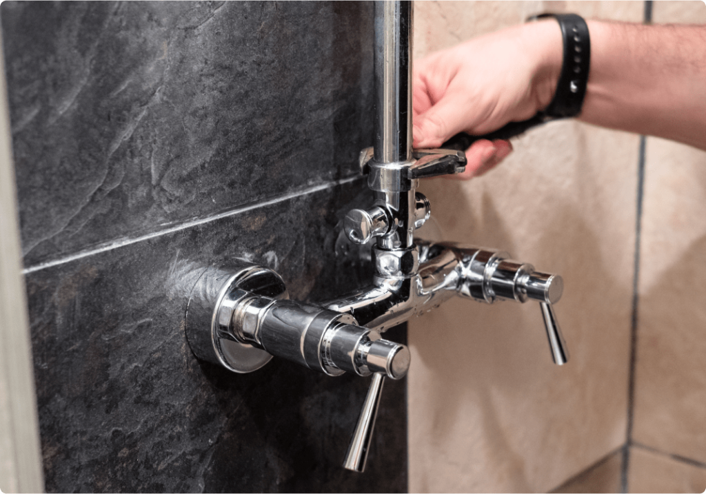 Man tightening a nut on a chrome shower diverter.