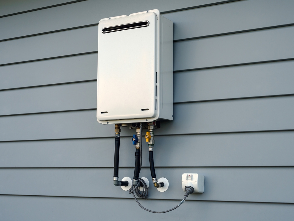 A tankless water heater mounted on the wall located on the outside of the home.