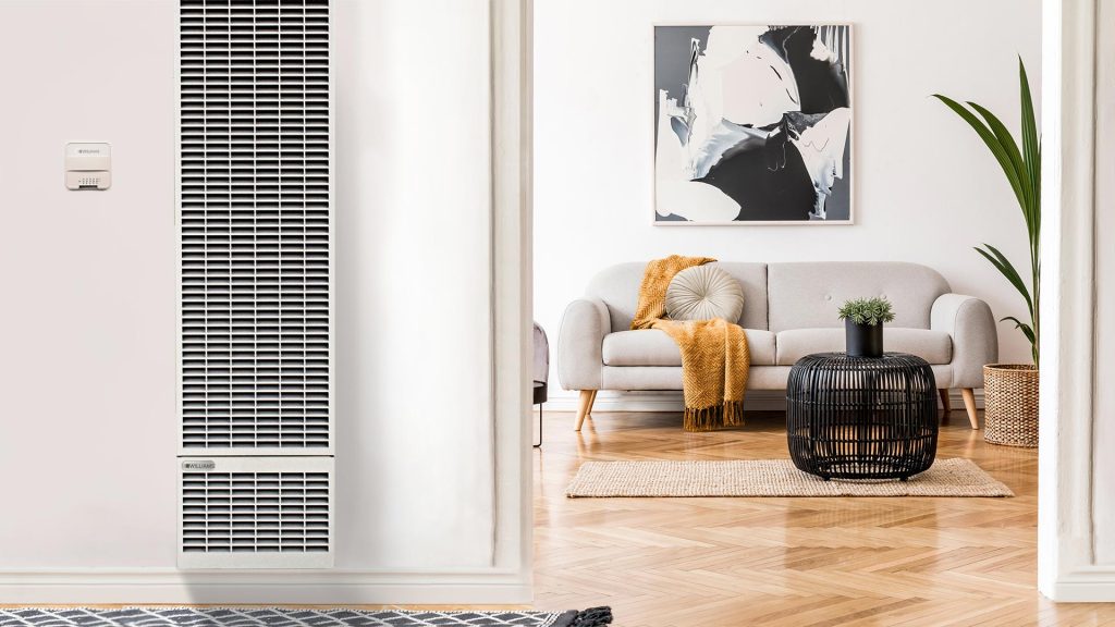 Modern wall heater located in a modern living room with a couch and decoration in the background.