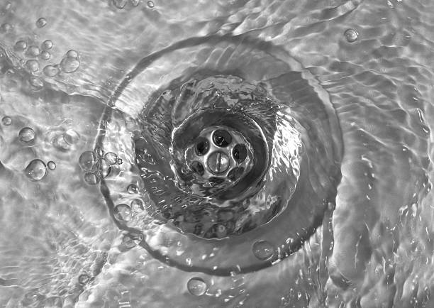 Close up of water swirling down a clean metal kitchen sink drain showing fast drainage.