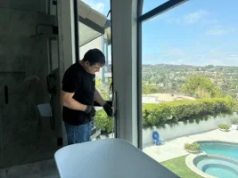 Plumbing technician installing a modern floor mounted tub filler for a freestanding bathtub in a bathroom with a scenic view.
